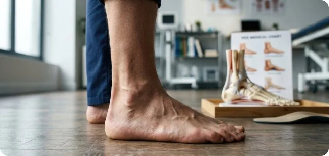 Custom orthotic and foot model next to a patient’s bare foot